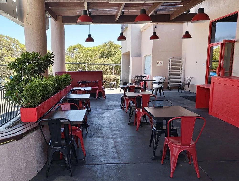 Covered outdoor patio with red tables and chairs outside Crazy Wings N Fries