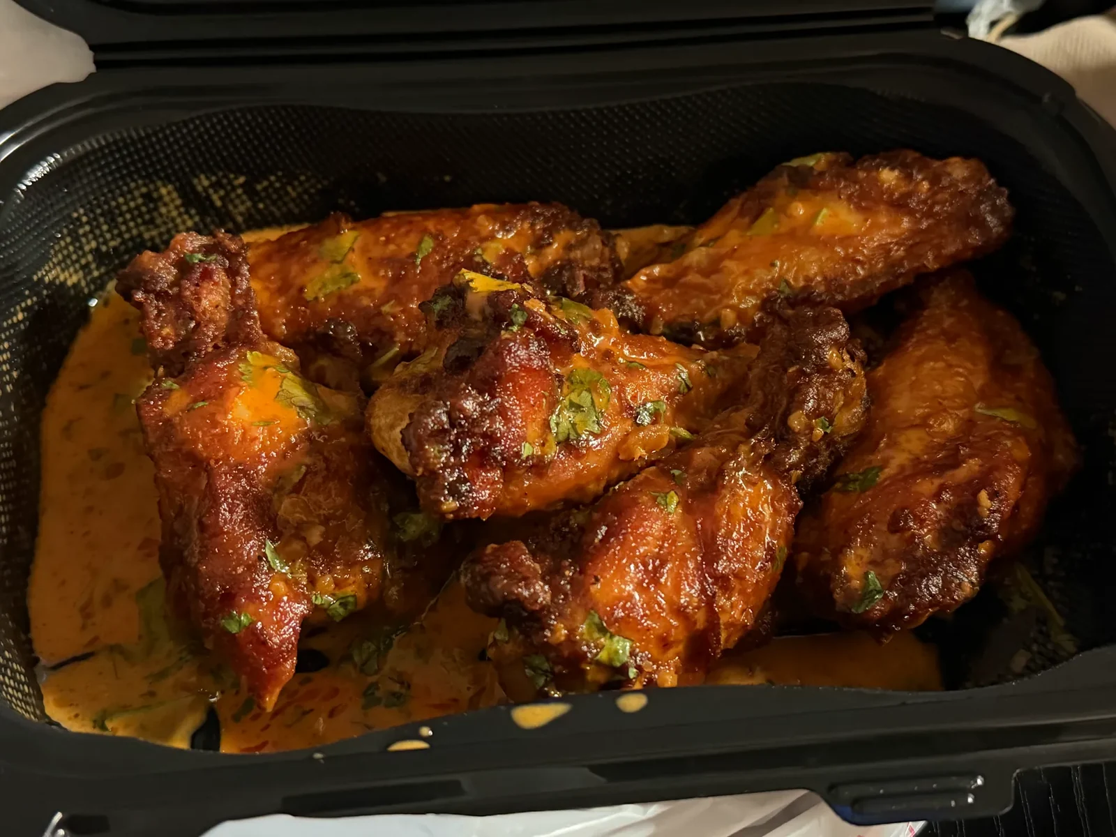 Sauced chicken wings in a takeout tray at Crazy Wings N Fries